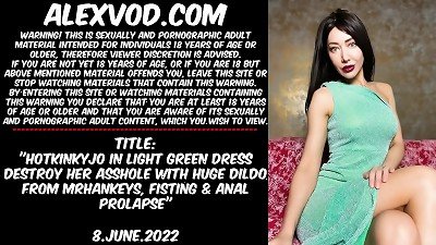A sexy woman in a light green dress uses a large fake penis to penetrate her vagina and perform fisting and anal penetration